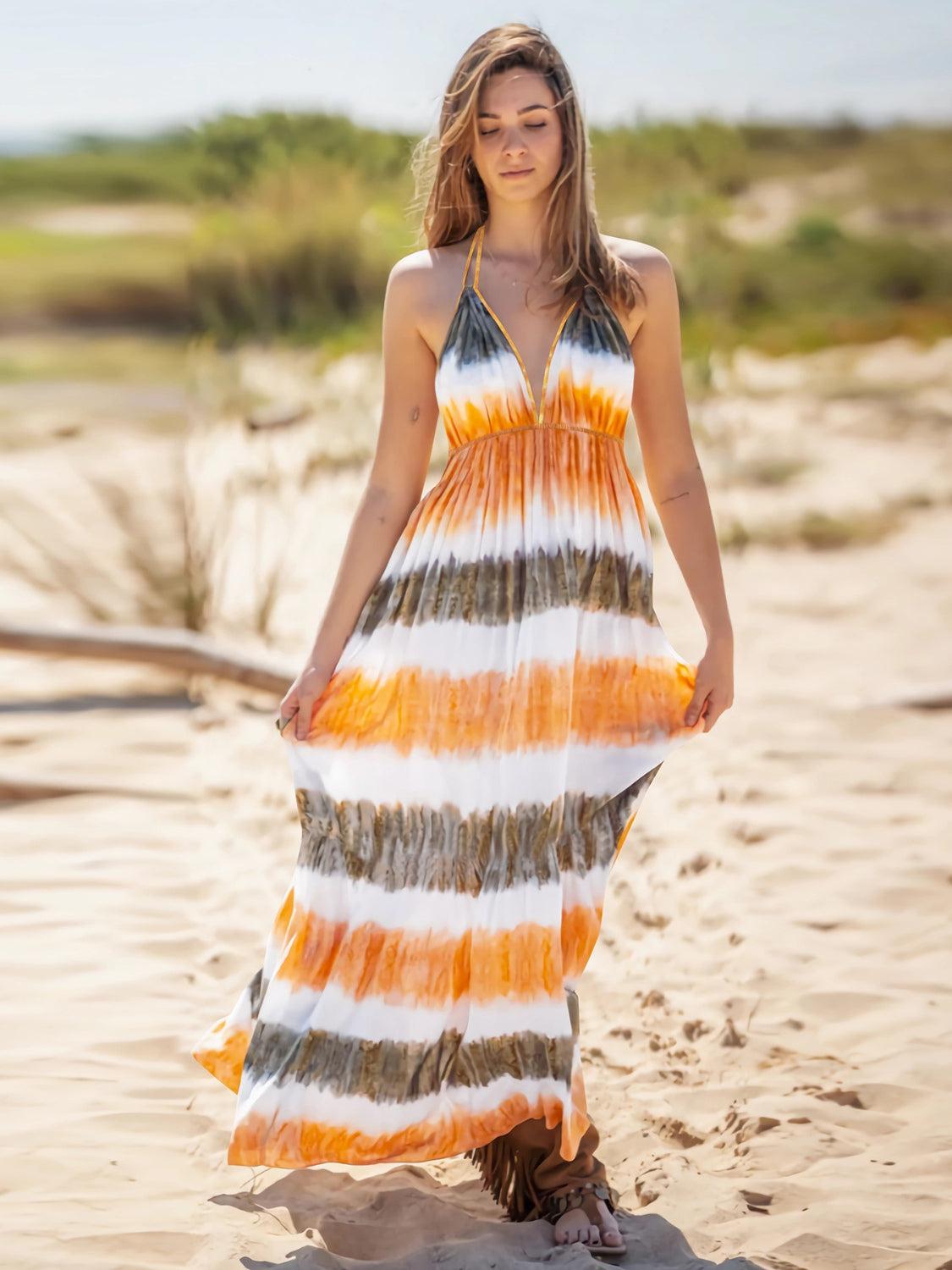 a woman standing in the sand wearing a dress