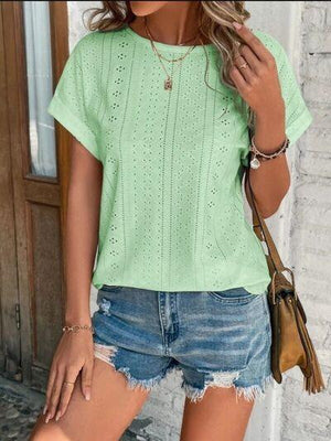 a woman wearing a green shirt and denim shorts