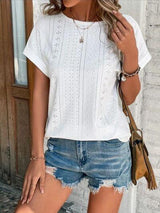 a woman wearing a white top and denim shorts