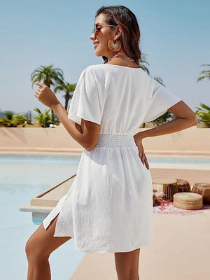 a woman in a white dress standing by a pool