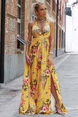 a woman in a yellow floral dress standing on a sidewalk