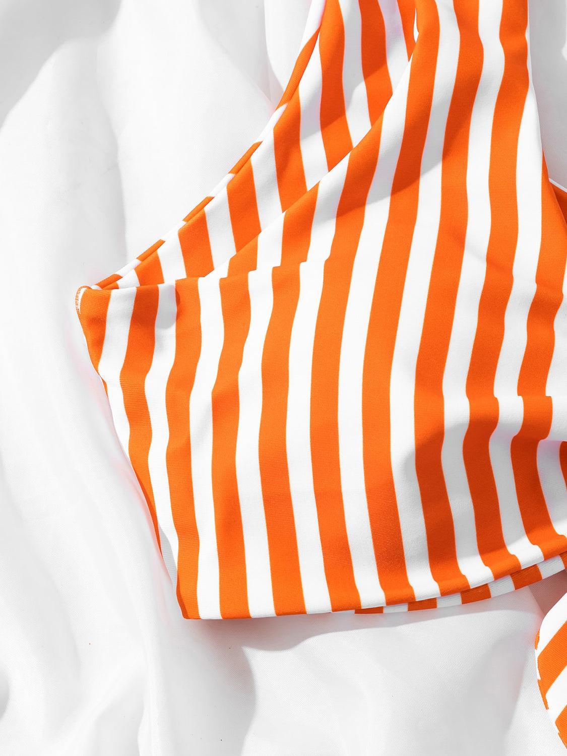 an orange and white striped fabric laying on top of a bed