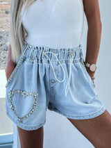 a woman wearing a white top and denim shorts