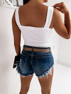 a woman in a white tank top and denim shorts