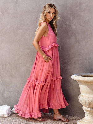 a woman in a pink dress leaning against a wall