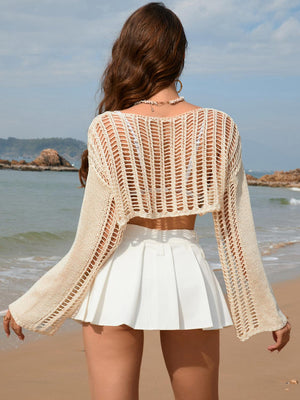 a woman standing on a beach with her back to the camera