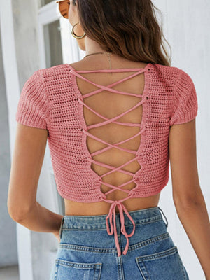 a woman wearing a pink top with a lace up back