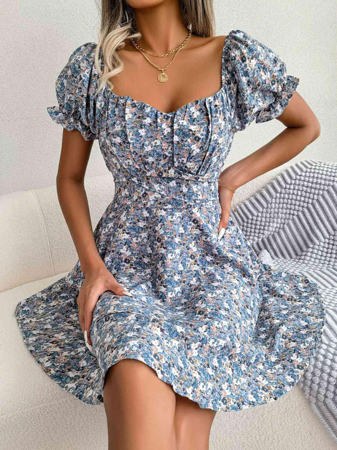 a woman in a blue floral dress posing for the camera