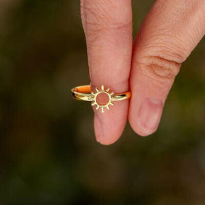 a person's hand holding a ring with a sun on it