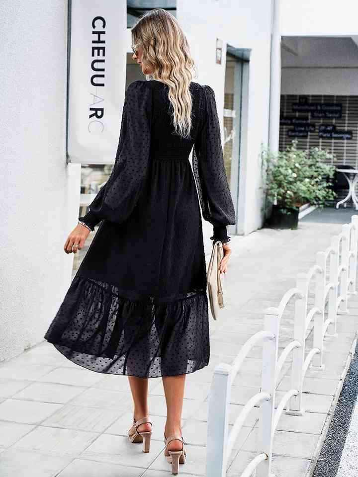 a woman in a black dress is walking down the street