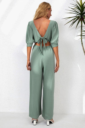 a woman wearing a green jumpsuit with a back cutout