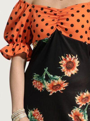 a woman wearing a polka dot top with sunflowers on it