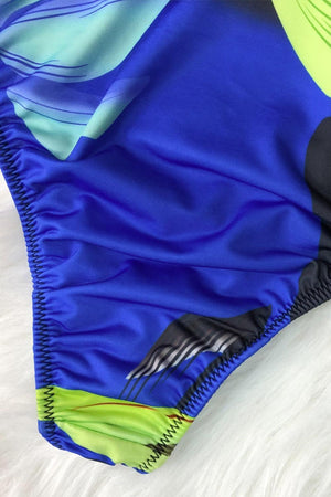 a close up of a blue and green swimsuit on a bed