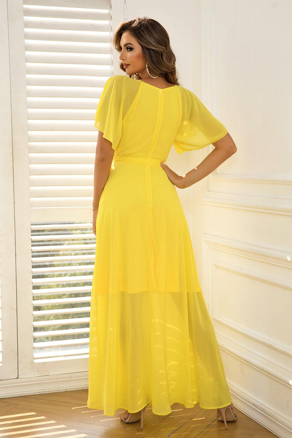 a woman in a yellow dress standing in front of a window