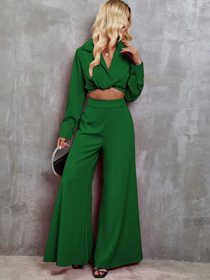 a woman in a green outfit leaning against a wall