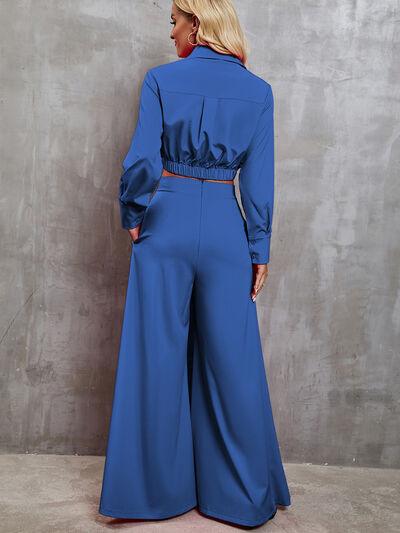 a woman in a blue jumpsuit standing against a wall