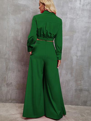 a woman in a green jumpsuit standing against a wall