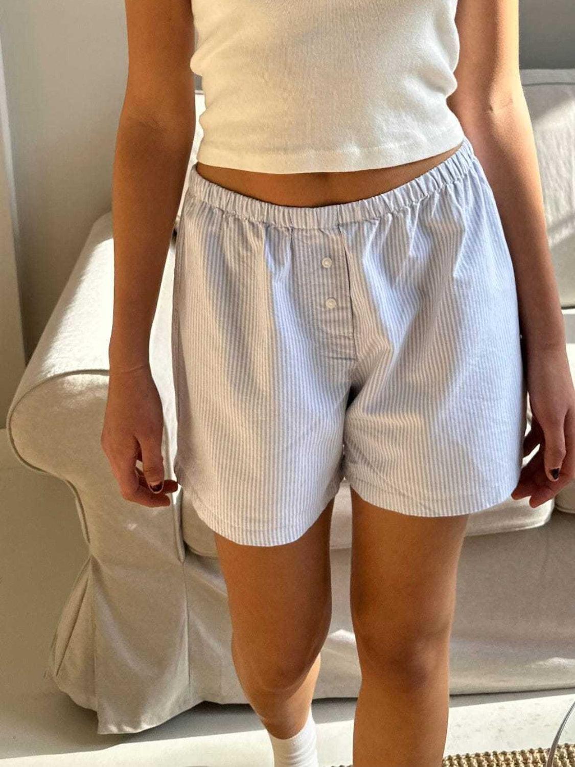 a woman in white shirt and shorts standing next to a bed