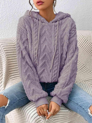 a woman sitting on a couch wearing a purple sweater