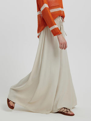 a woman in an orange sweater and white skirt