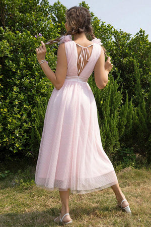 a woman in a pink dress standing in a field