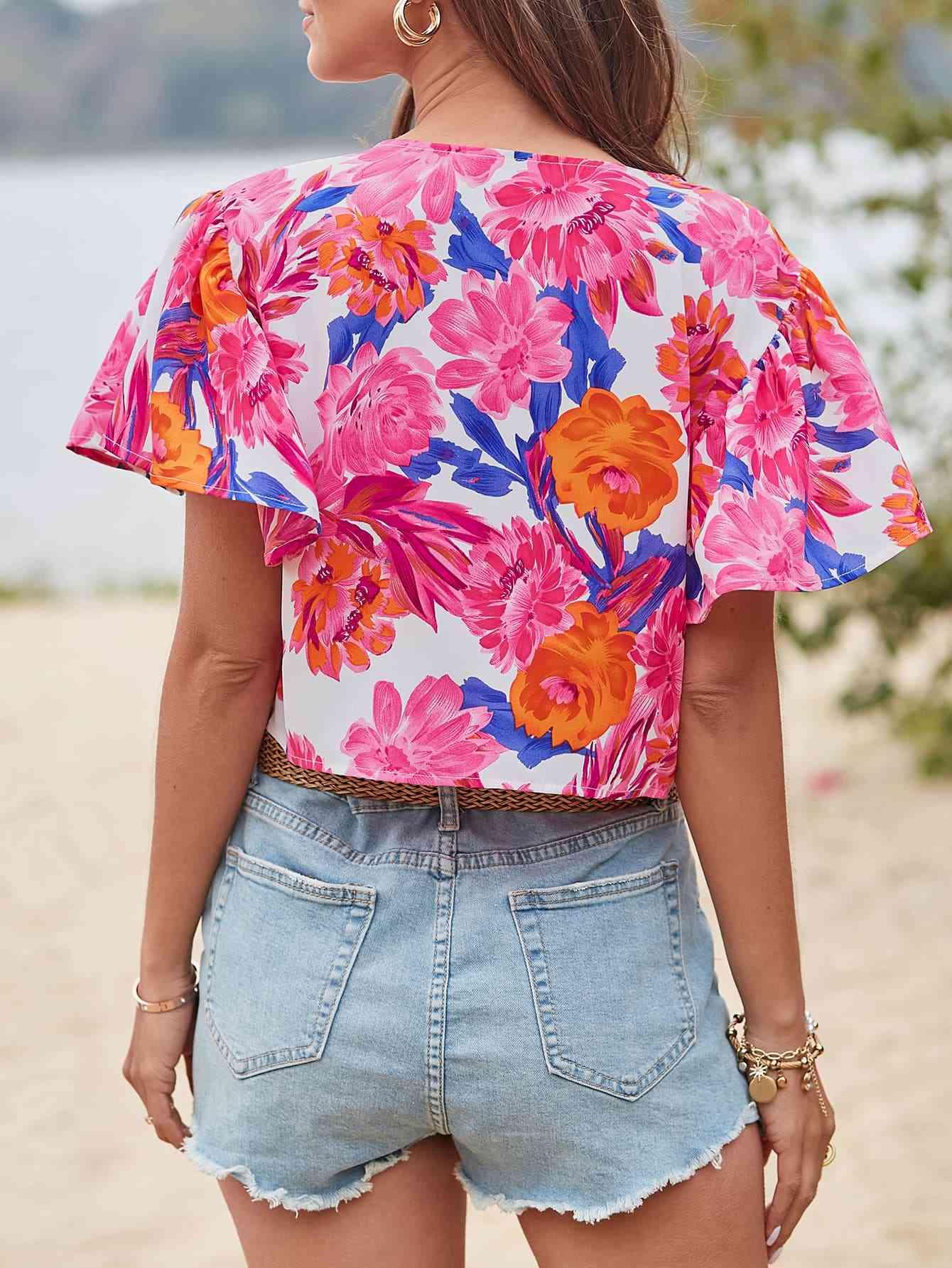 a woman standing on a beach wearing a floral top