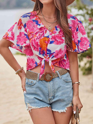 a woman wearing a floral top and denim shorts