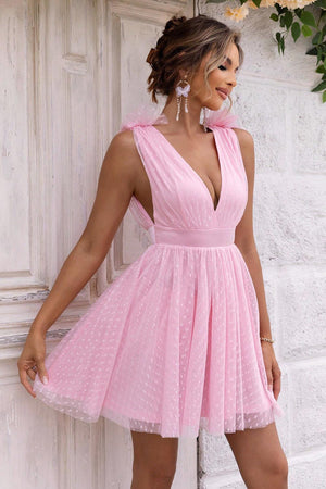 a woman in a pink dress leaning against a wall