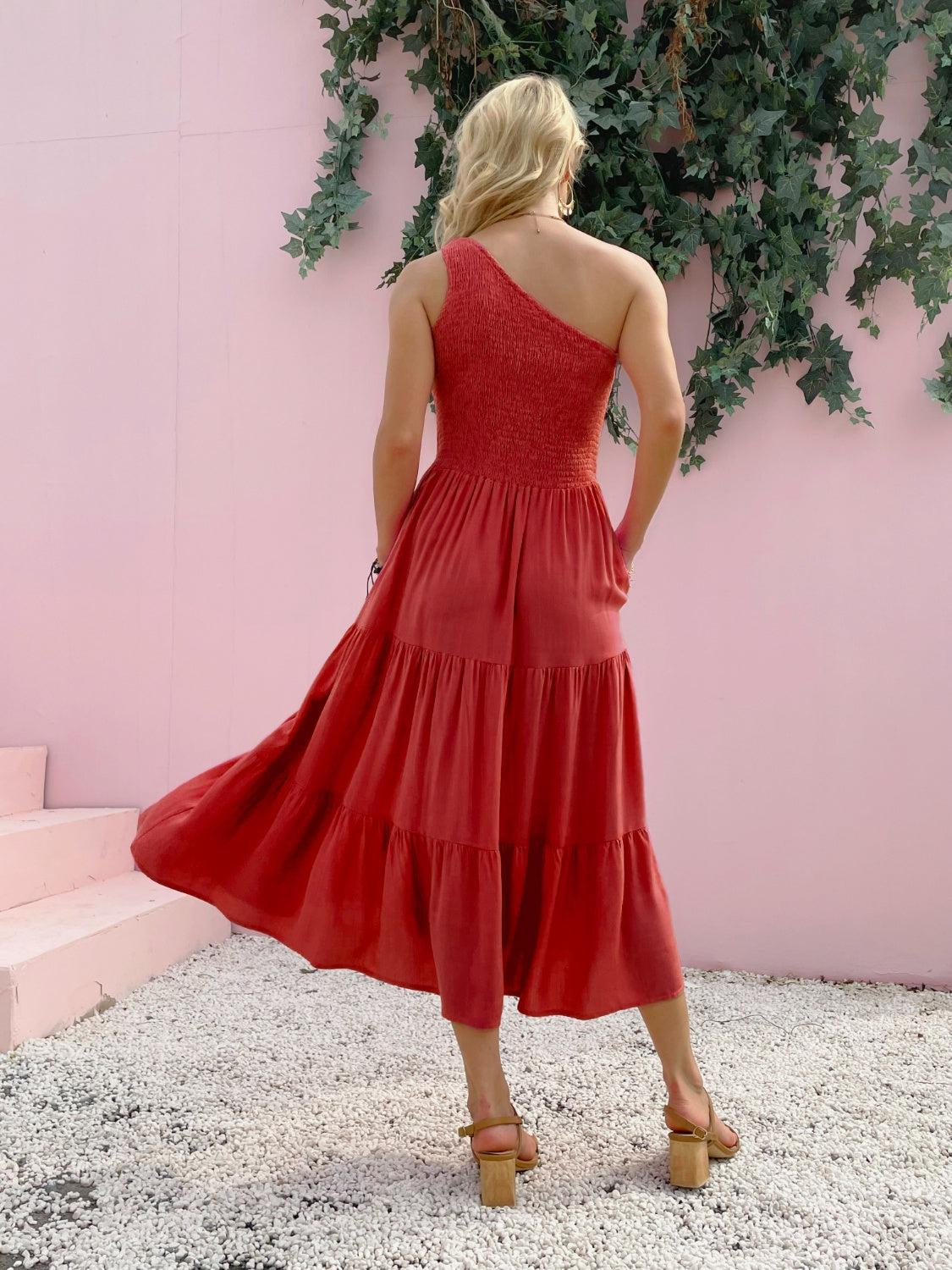 a woman in a red dress standing in front of a pink wall