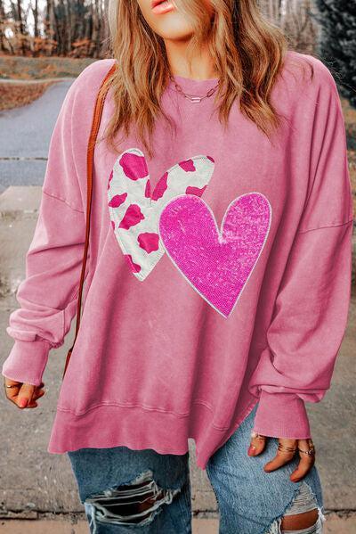 a woman wearing a pink sweatshirt with a heart on it