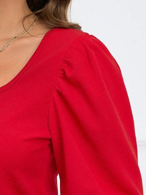 a woman wearing a red top and a gold necklace