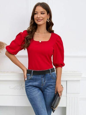 a woman in a red top and jeans posing for a picture