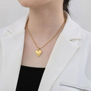a woman wearing a white jacket and a gold heart necklace