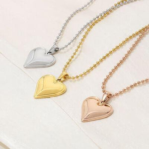 three heart shaped pendants on a white surface