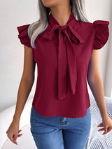 a woman wearing a red top with a bow tie