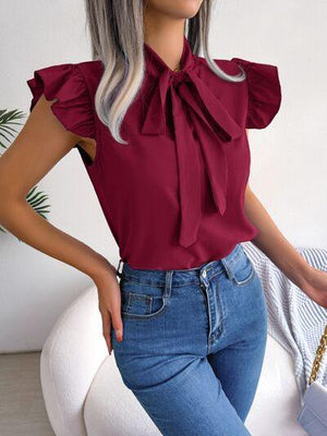 a woman with grey hair wearing a red blouse and jeans