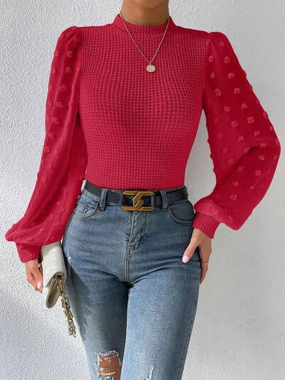 a woman wearing ripped jeans and a red top