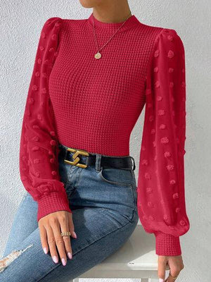 a woman sitting on a chair wearing a red top