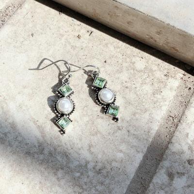 a pair of earrings sitting on top of a cement floor