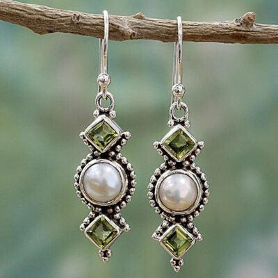 a pair of earrings with pearls and green stones
