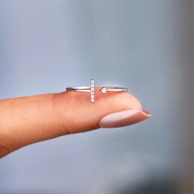 a person's hand holding a tiny ring with a cross on it