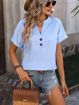 a woman wearing a blue shirt and denim shorts