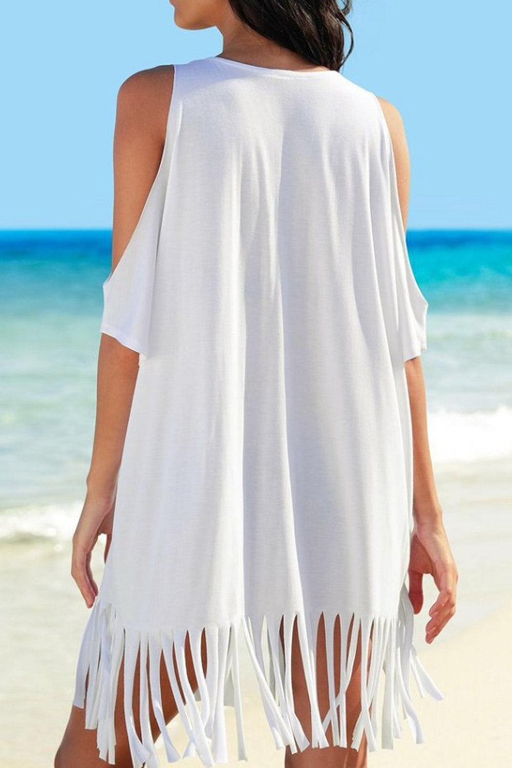 a woman standing on a beach wearing a white dress