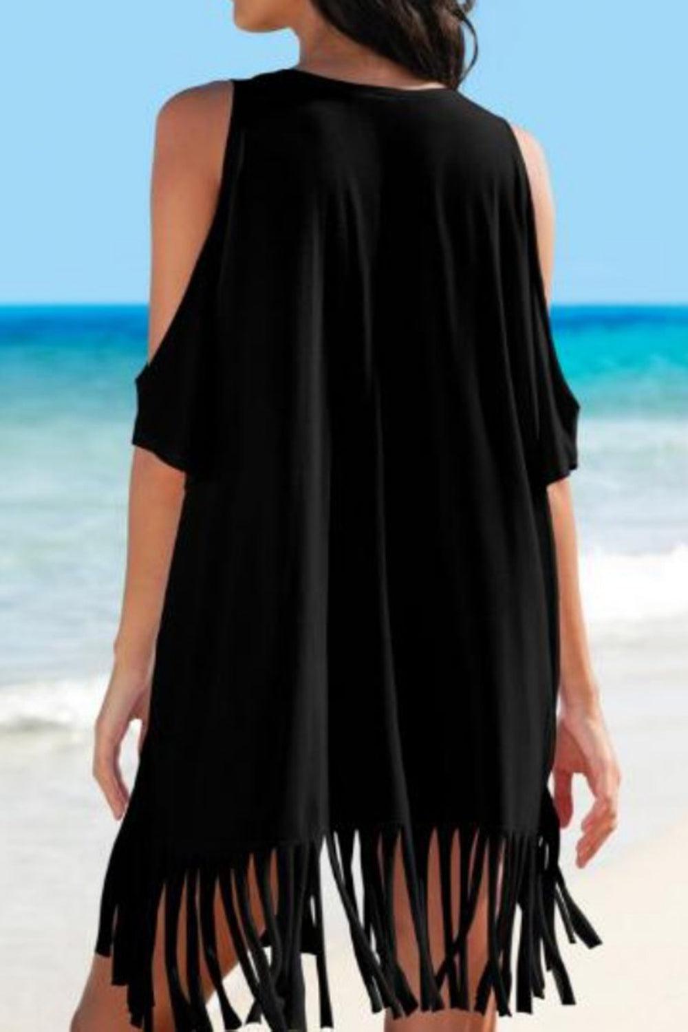 a woman standing on a beach wearing a black dress