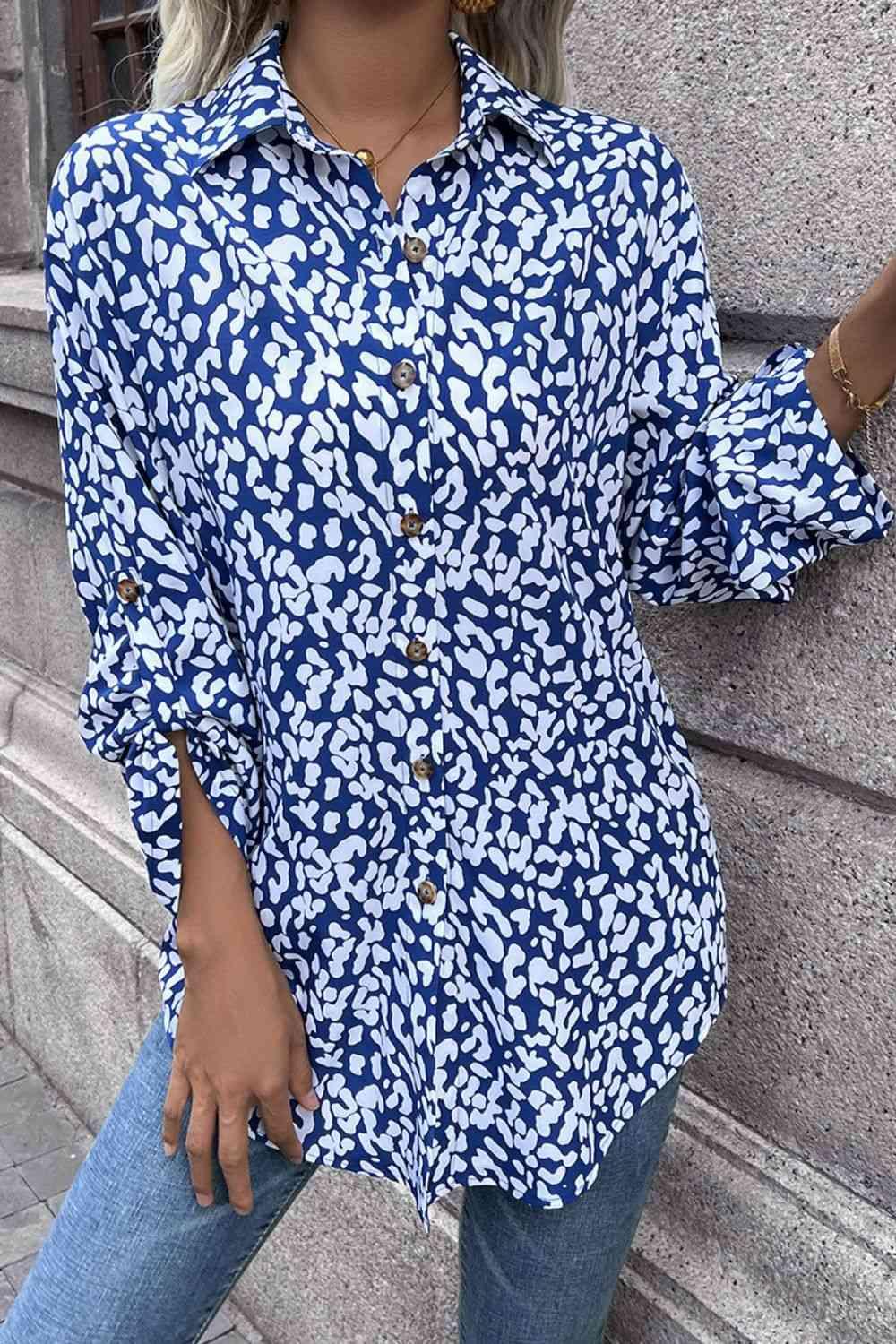 a woman leaning against a wall wearing a blue and white shirt