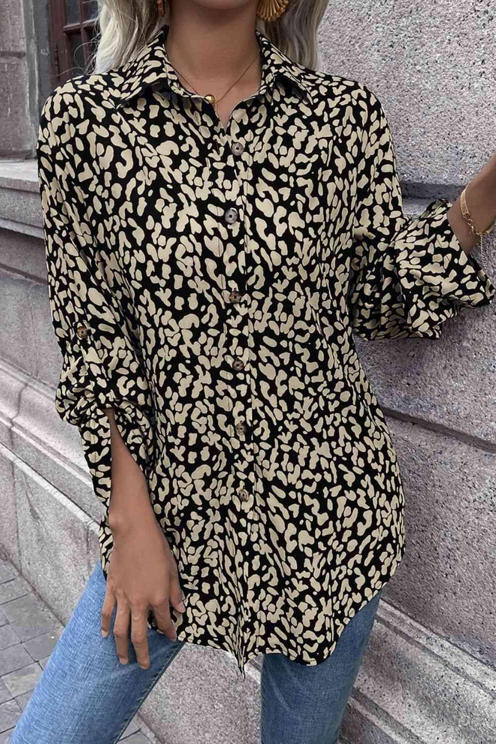 a woman standing next to a wall wearing a black and gold shirt