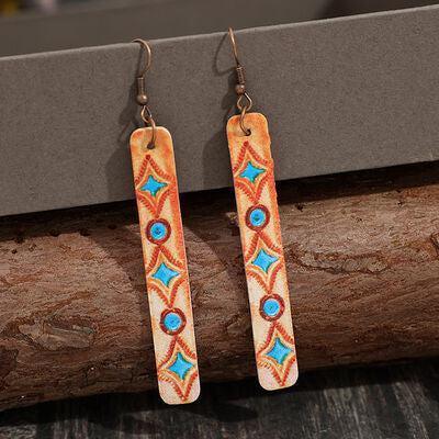 a pair of earrings hanging from a piece of wood
