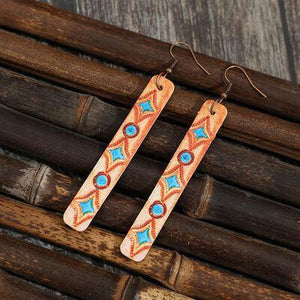 a pair of wooden earrings with blue and orange designs