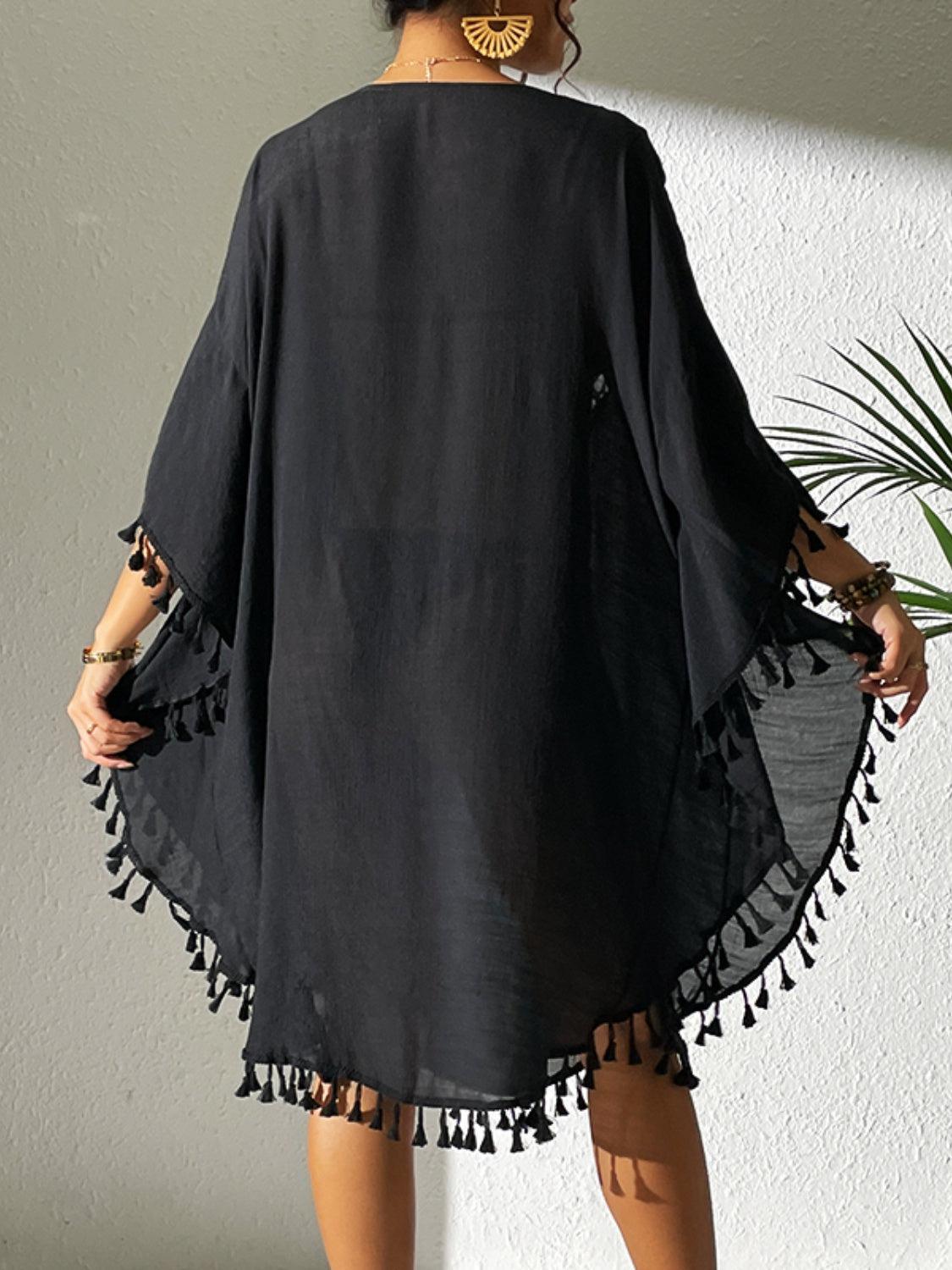 a woman wearing a black dress with tassels