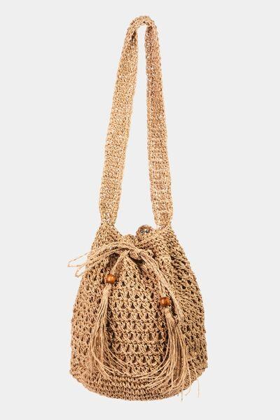 a straw bag with a tasselled handle